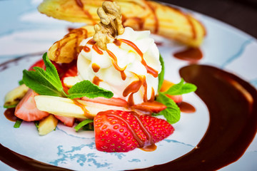 Close up delicious dessert with waffle rolls, ice cream and strawberries