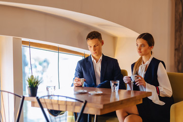 A stylish couple drinks morning coffee at the cafe, young businessmen and freelancers