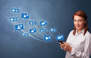 Young person using phone with flying social media icons around
