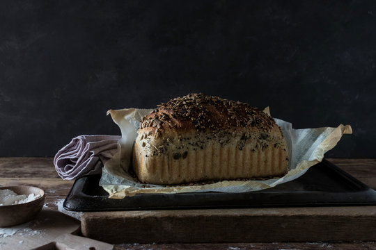 Loaf of delicious rye bread with seeds lying on timber tabletop