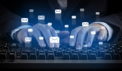 Business woman typing on keyboard with mail icons around
