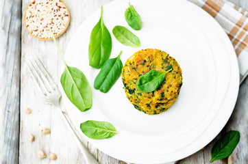 Quinoa spinach chickpeas pumpkin fritters on a wood background