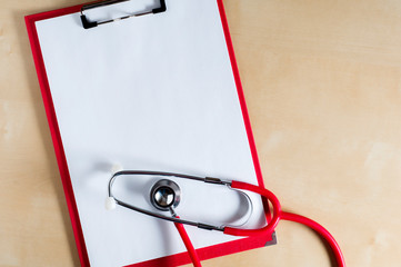 Red stethoscope on a red clipboard. Top view. Medical device. Treatment, health care. Heart examination. Studying the pulse.