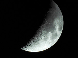a crescent moon with clear visibility reveals many craters on the surface