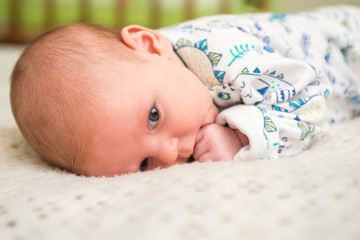 Portrait of a cute baby lying down on a bed. New family and love concept. Happy toddler in bodysuit