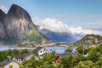 Lofoten, Blick über Reine, norwegische Häuser, Fjord mit Bergen im Hintergrund