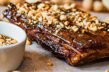 Close up board with pork ribs grilled with BBQ sauce and peanuts
