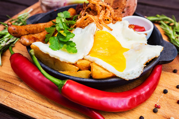 Meal with fried egg, sausages, beans, onion rings, chili pepper and sauce