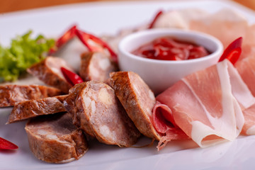 Cutting bacon, sausage, prosciutto and cured meat on a celebratory table