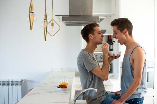Affectionate gay couple having healthy breakfast at home in the kitchen