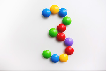 Digit 3 made from children's toys. Multicolored figures for games