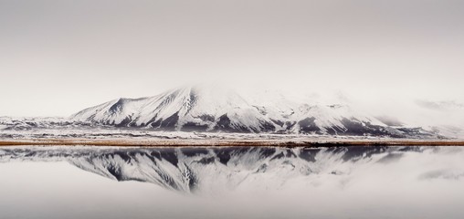 Picturesque view of lake and coast with snowy mountain in Iceland