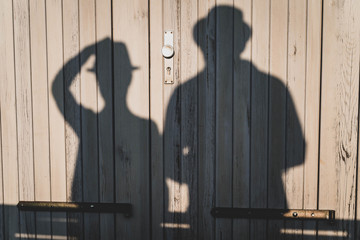 The shadow of a couple with hats on a wooden door/gate