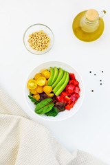 Fresh vegetable salad on the white table. Sliced tomatoes, avocado and pepper with greens.