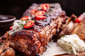 Delicious barbecued ribs seasoned with fresh herbs, cabbage salad, backed potato on an old rustic wooden chopping board