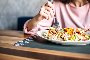 Woman eating at the restaurant, closeup of big mixed salad plate