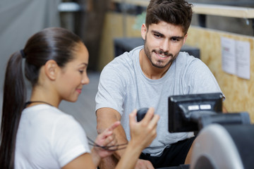 man and woman doing exercises with rowing machine at gym