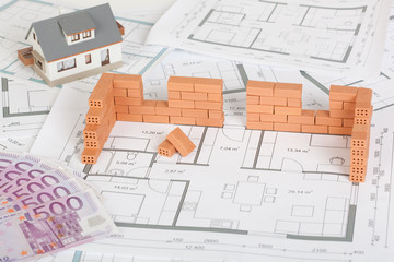Model house construction with brick on blueprint and five hundred euro banknote