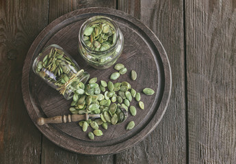 pumpkin seeds in glass jars and on a wooden background top view. pumpkin seeds on the table. copy space.
