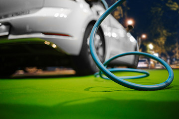 Naklejka premium Electric vehicle at charging station. Focus on cable