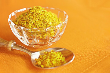 spice mix in glass cup and spoon close up. yellow background with yellow spices.