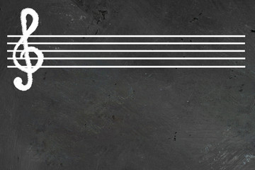 White blank musical five lines staff with violin cleff on it on black chalkboard. Horizontal with...