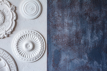 A two-color background, gray decorative plaster and a white wall with several white ceiling rosettes