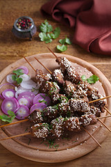Obraz na płótnie Canvas Beef liver on skewers with sesame seeds on wooden tray. Liver Kebab, kabob - image