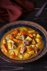 Homemade beef stew with vegetables in bowl on wooden table