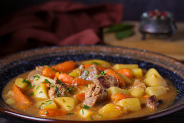 Homemade beef stew with vegetables in bowl on wooden table