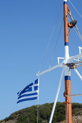 Greek flag on the mast of a sailing boat. Travelling in the blue sea, summer in Greece.