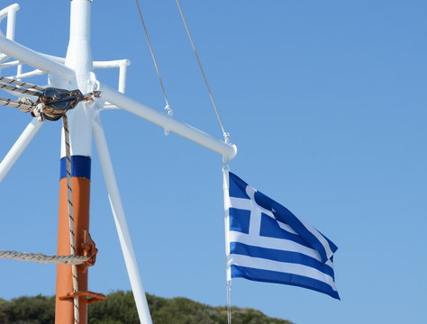 Greek flag on the mast of a sailing boat. Travelling in the blue sea, summer in Greece.