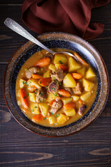 Homemade beef stew with vegetables in bowl on wooden table