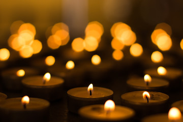 soft focus candle light in darkness on yellow bokeh blurred background atmospheric church interior...