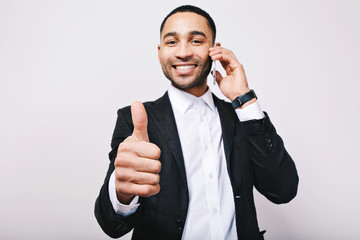 Successful time of young handsome man in white shirt, black jacket expressing positivity to camera on white background. Talking on phone, leadership, great career, manager, cheerful mood