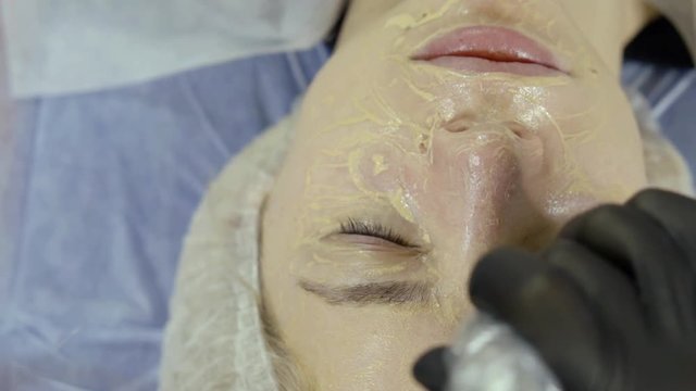 woman is relaxing in cosmetological office during treatment of skin care for face, closeup view