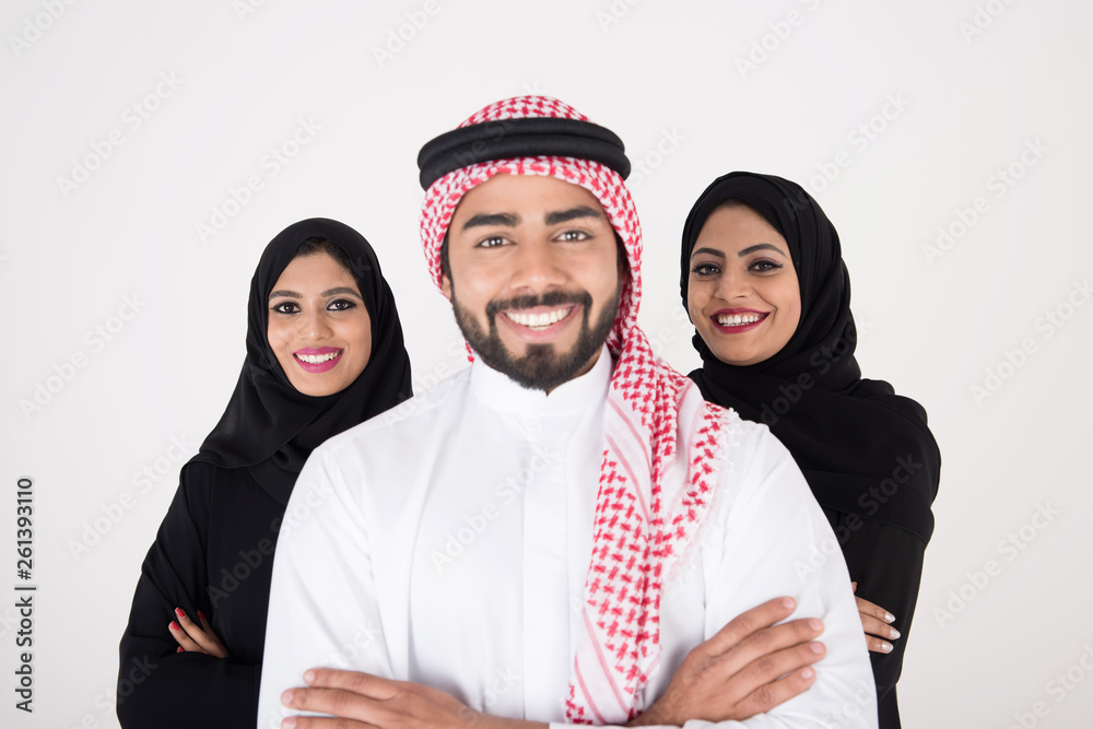 Wall mural two arab females with one male smiling and standing on white background