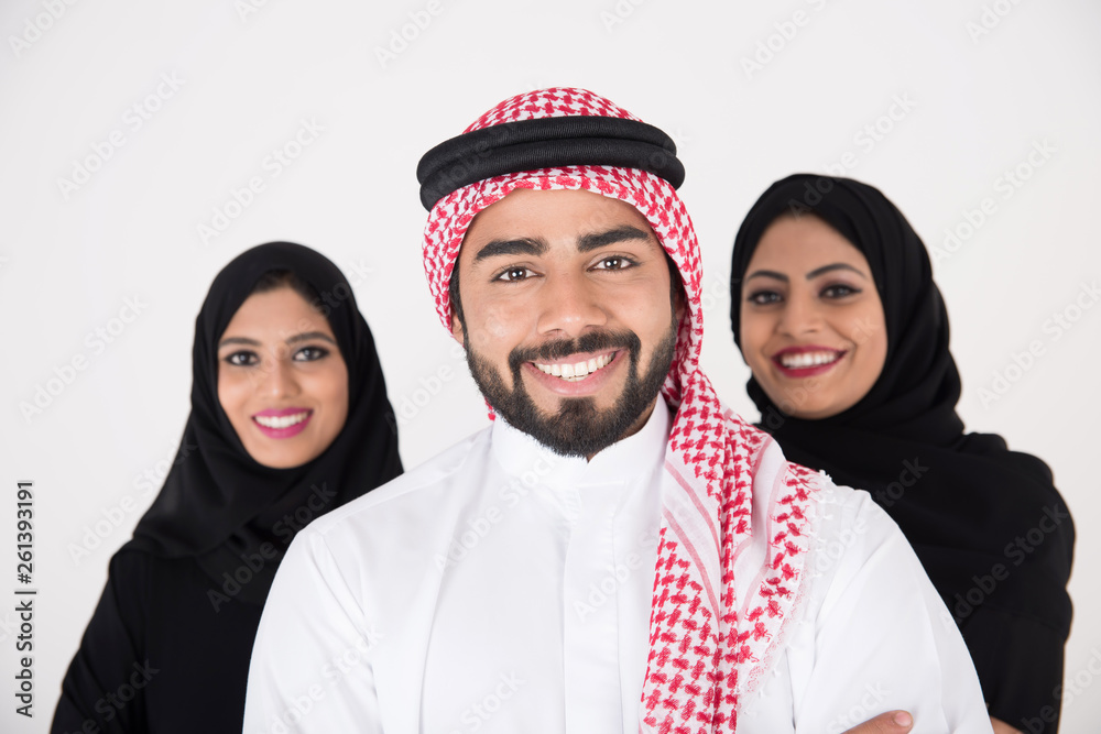 Wall mural two arab females with one male smiling and standing on white background