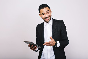 Obraz na płótnie Canvas Stylish young handsome man in white shirt, black jacket, with tablet smiling to camera on white background. Achieve success, great work, expressing true positive emotions, businessman, smart worker