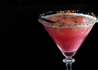 glass with red alcohol drink and straw isolated on black