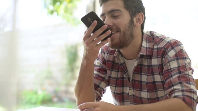 Close-up shot of young man sending voice message and using an emojis while chatting on smartphone