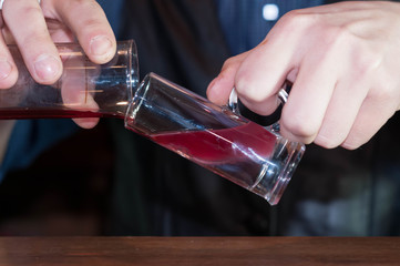 cropped view of barman at counter making alcohol cocktail in bar 