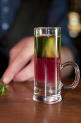 selective focus of shot glass with alcohol drink and rosemary on wooden counter in bar