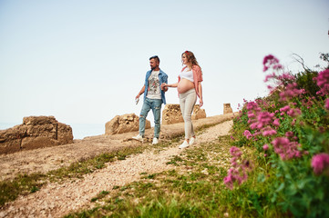 Young pregnant woman walking with her husband in a park
