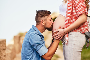 Young man kissing his pregnant wife's belly