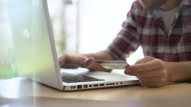 Mid section of young man using a laptop while making online payment through credit card at home