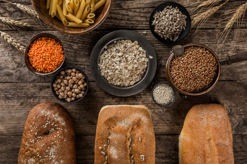 Fototapeta na wymiar Different fresh bread and Cereals on rustic wooden background. Creative layout made of bread. Healthy food concept, top view, flat lay, copy space