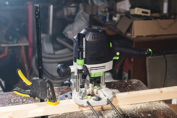 Close-up electric router milling machine in a dark room of a home craft workshop