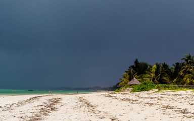 Tropical beach with silhouettes of people in the distance