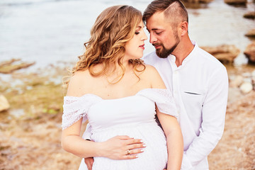 Portrait of a young pregnant woman posing with her husband on the beach